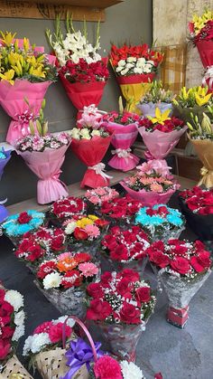 a bunch of flowers that are sitting on the ground in front of some baskets and vases