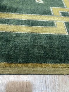 a green and yellow area rug on the floor with wood flooring in the background