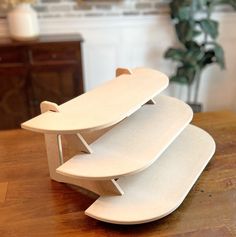 three surfboards stacked on top of each other on a wooden table next to a potted plant