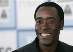 a close up of a person wearing a suit and tie smiling at the camera with a blue wall in the background