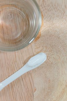 a white toothbrush sitting on top of a wooden table next to a glass bowl