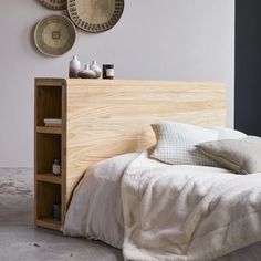 a bed with white linens and pillows in a bedroom next to two baskets on the wall