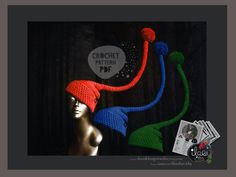 a crocheted hat with two pom poms on top of it, next to a mannequin's head