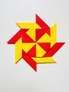 an origami bird made out of red and yellow paper on a white surface