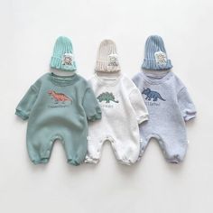 three baby onesuits with dinosaurs printed on them, one is blue and the other has