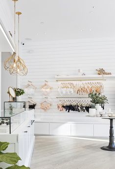 the inside of a shoe store with white walls and wooden flooring, plants on display