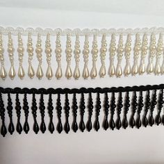 black and white beaded trim with pearls hanging from it's sides on a wall