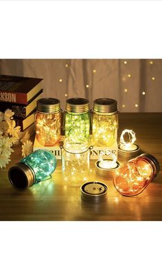 mason jars filled with fairy lights sitting on top of a table next to books and flowers