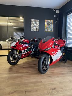 two red motorcycles parked in a showroom next to each other on hard wood flooring