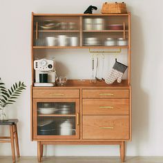 a wooden cabinet with glass doors and shelves above it, next to a small chair