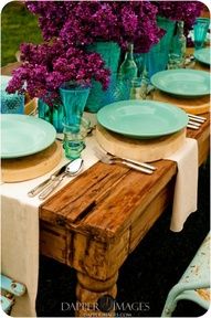 the table is set with green plates and purple flowers