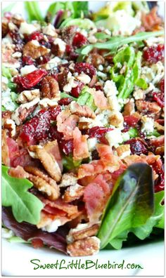 a salad with bacon, lettuce and cranberries in it on a white plate