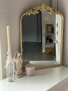 a mirror sitting on top of a dresser next to a candle