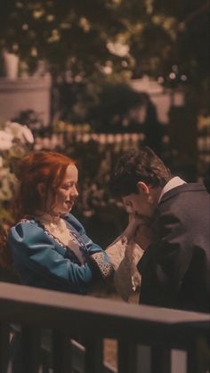 a man and woman sitting on a bench in the dark, looking at each other