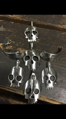 several metal skulls are hanging on a wooden wall