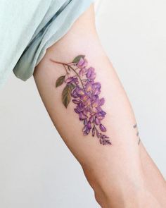 a woman's arm with purple flowers and leaves on the back of her arm