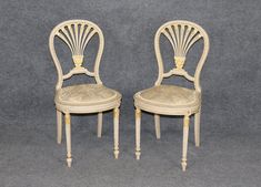 two white chairs sitting next to each other on a gray surface with one chair up against the other