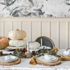 a table topped with white plates and pumpkins