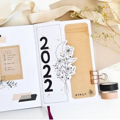 an open planner book with flowers and writing on the pages, next to a ribbon