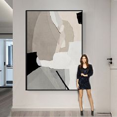 a woman standing in front of a painting on the wall with her arms crossed and looking at the camera