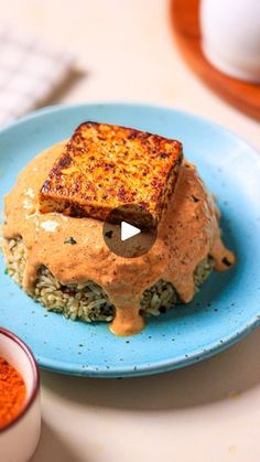 a blue plate topped with grilled cheese covered in gravy on top of rice