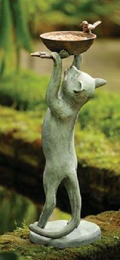 a statue of a dog holding a bowl on its head with one paw and the other hand