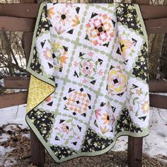 a quilt hanging on a wooden fence in the snow