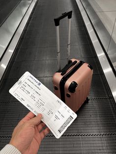 a person is holding a ticket and luggage at an escalator in the airport