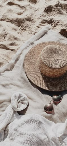 a hat, sunglasses and scarf laying on the sand