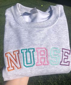 someone holding up a t - shirt with the word nurse on it in multicolored letters