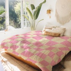 a bed with pink and yellow plaid comforter in a bedroom next to a window