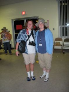 two women standing next to each other in front of a doorway with people walking around