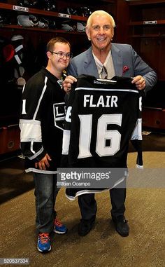 an older man holding up a hockey jersey with a young boy standing next to him