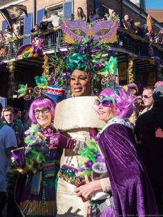 two women dressed in purple and green at a mardi gras parade