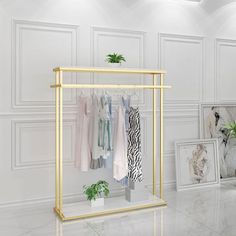 an empty room with clothes hanging on the rack and plants in vases next to it