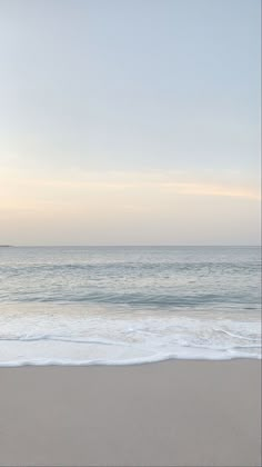 an empty beach with the ocean in the background