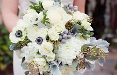 a bridal holding a bouquet of white flowers and greenery