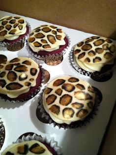 several cupcakes with white frosting and brown animal print designs on them in a box