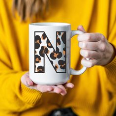 a person holding a coffee mug with the letter n on it