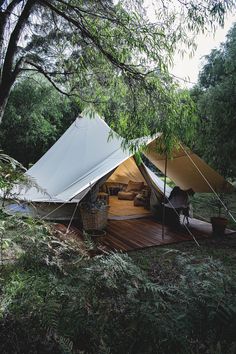 a tent is set up in the woods for people to relax and watch from inside