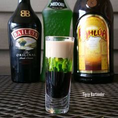 an alcoholic drink is sitting on a table next to liquor bottles