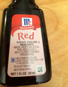 a bottle of red food color sitting on top of a wooden table