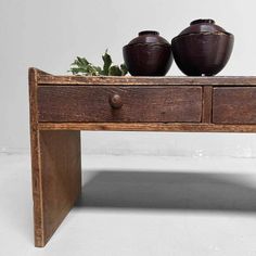 two brown vases sitting on top of a wooden table