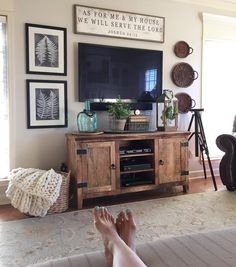 a person's feet resting on the floor in front of a flat screen tv