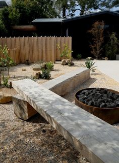 a wooden bench sitting in the middle of a gravel covered area next to a fence