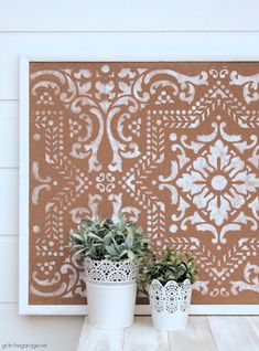 two potted plants sitting on top of a white table next to a brown and white wall