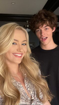 a man standing next to a woman with long blonde hair and smiling at the camera