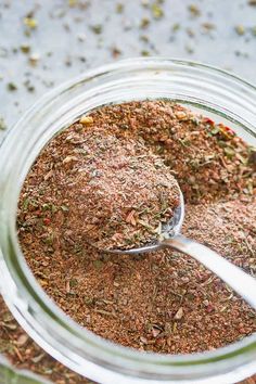 a glass jar filled with spices and a spoon full of seasoning next to it