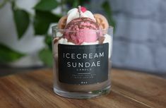 an ice cream sundae sits in a glass container on a table next to a potted plant