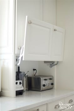 a kitchen with white cabinets and appliances in it